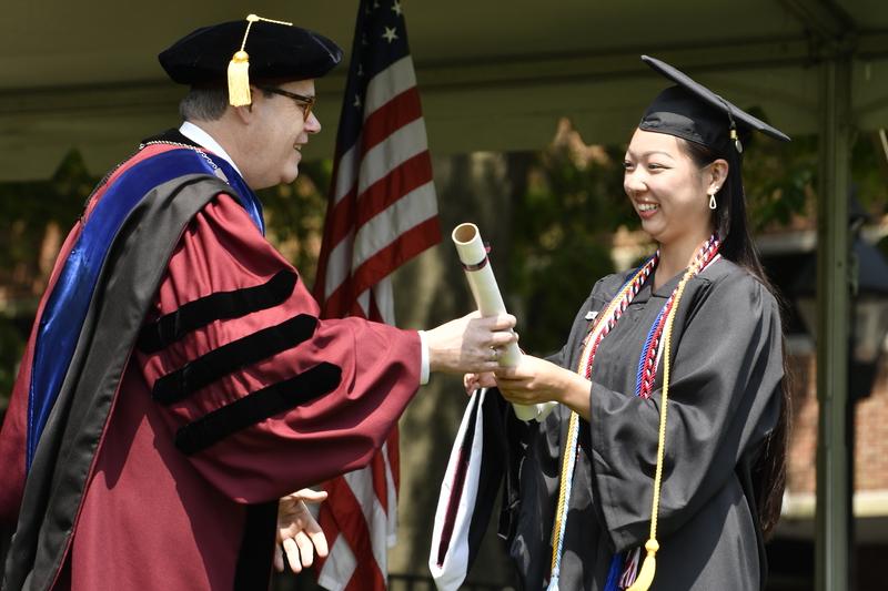 Sammy Segeda accepts her diploma from President Mike Sosulski while crossing the stage at the 2023 Commencement ceremony.